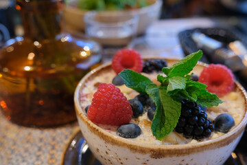 natural oatmeal porridge with milk and fresh raspberry and blueberry and mint for breakfast, health care, organic food