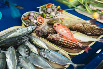 Different kinds of newly harvested fish is displayed for sale together with some spices at the side.