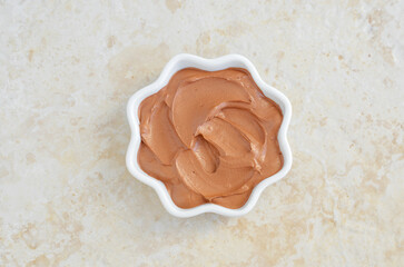 Red moroccan bentonite clay in a small white bowl. Diy facial or hair mask, body wrap recipe....