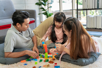 Asian family portrait There are parents and daughters playing block puzzles at home together having fun and happiness.