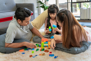 Asian family portrait There are parents and daughters playing block puzzles at home together having fun and happiness.