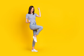Fototapeta na wymiar Full size photo of satisfied overjoyed lady raise arm leg yelling yeap win lottery stand empty space isolated on yellow color background