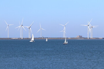 Wind power: sailing ships on the Eastern Scheldt estuary and wind turbines on the storm surge barrier, Netherlands