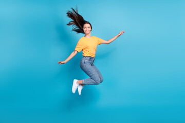 Full length photo of sweet shiny lady wear yellow t-shirt jumping high arms sides empty space isolated blue color background