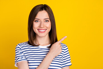 Portrait of gorgeous nice lovely woman straight hairdo dressed striped t-shirt directing empty space isolated on yellow color background