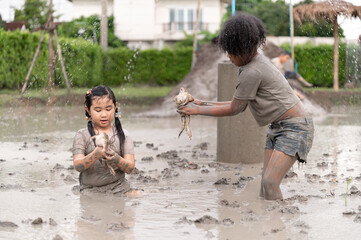 Funny kids girl holding fog with playing in mud puddle	
