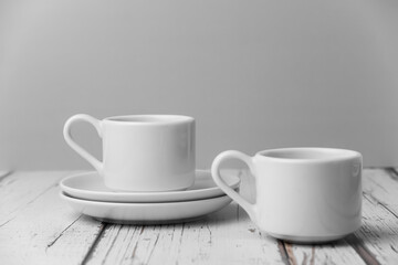 a set of white ceramic tableware on a light background. Various types of white plates, bowls and platters, cups, saucers, milkmen. Simple white tableware for use at home or in a cafe.
