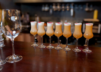 Alcohol cocktail gold color shots in small champagne glasses bar desk