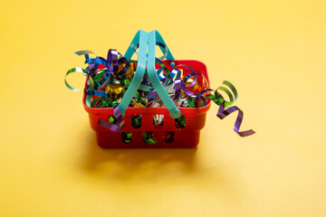Christmas sale concept with shopping basket full of colorful tinsel on color background