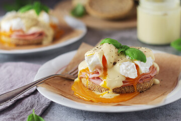 Egg benedict sandwiches - muffin with poached egg, ham and hollandaise sauce