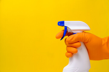 Sprayer for cleaning windows and plumbing in hand with glove on yellow background.