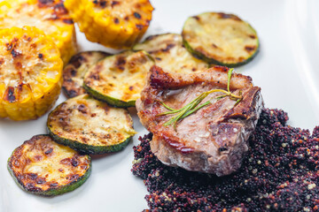 grilled pork steak with zucchini and corn served with black quinoa
