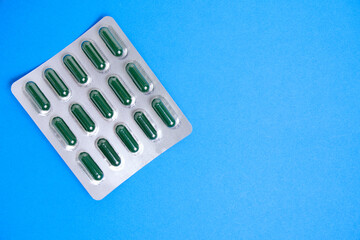 Green pills in package blue background.