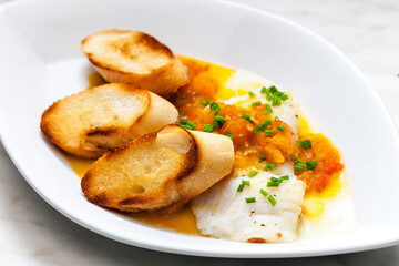 white fish with tomato sauce and roasted baguette slices