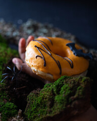 orange donut with spider and bat hand in ground moss halloween