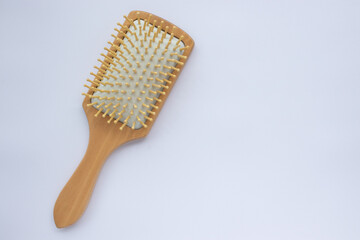 Wooden comb on white background. Modern paddle hair brush on table. Top view, flat lay, copy space. 