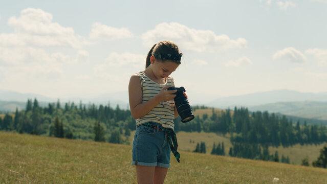 Young photographer shooting landscape on beautifull green hillway, taking pictures of nature. Girl filling the portfolio with amazing photos, spending leisure time outdoor.