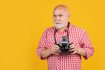 sad old man with retro photo camera on yellow baqckground