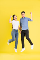 full body image of asian couple posing on yellow background