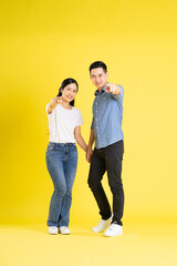 full body image of asian couple posing on yellow background