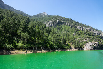 Fototapeta na wymiar View of the lake with green water and on the mountain cliffs of the Green Canyon. Landscape of Green canyon, Manavgat, Antalya, Turkey