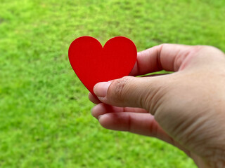 Fototapeta na wymiar Red heart shaped with hand holding it background. Stock photo.