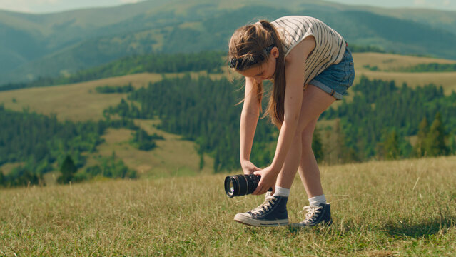 Young photographer filming beautiful movie. Girl creating content in motion, wathing results and feeling happy, spending leisure time outdoor