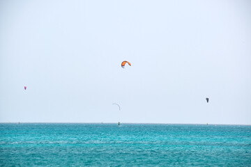 People sportsmen windsurfing and kite surfing in blue ocean water. Summer extreme exotic sport concept