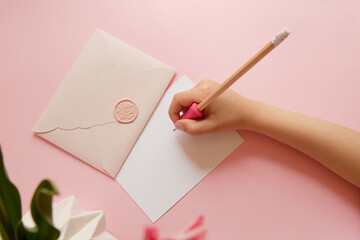 Top view of hands of anonymous child holding pink envelope with gift certificate.Good for mother day.