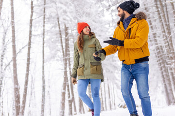 Fototapeta na wymiar Couple taking a walk through a forest on snowy winter day