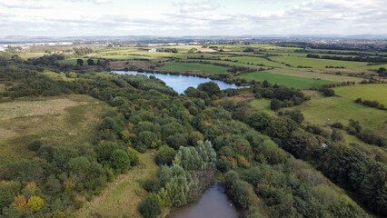 Aerial view of green countryside with a lake surrounded by trees. Taken in Bury Lancashire England. 