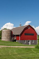 Red barn with brown shingled roof and  old silo on a farm in rural Minnesota, USA.
