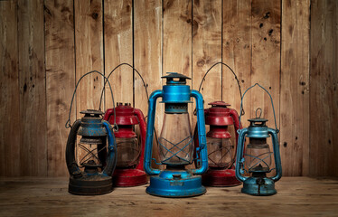 Five antique kerosene lamps red and blue in antique rustic country barn with wood wall background.