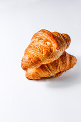 Two fresh soft golden croissants on a white background. Crispy French pastries in butter. Creative concept of food for breakfast