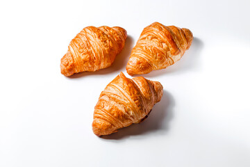 Three fresh golden croissants in butter on a white background with room for text. Creative concept of soft pastries and bread for breakfast