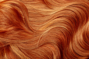 Fototapeta premium Red hair close-up as a background. Women's long orange hair. Beautifully styled wavy shiny curls. Hair coloring bright shades. Hairdressing procedures, extension.