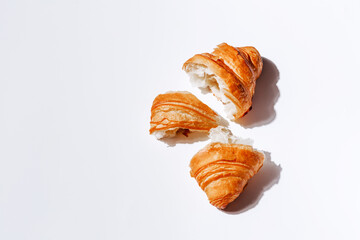 Pieces of croissant on a white background with room for text. Soft and fresh pastries top view