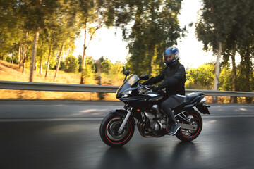 Side view of a biker riding on the road with motion blur.