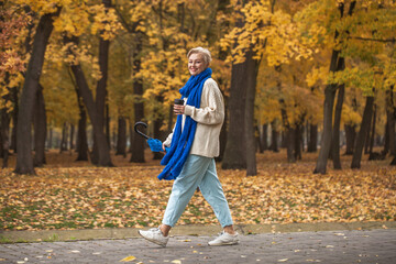 Beautiful middle-aged woman walking in autumn park