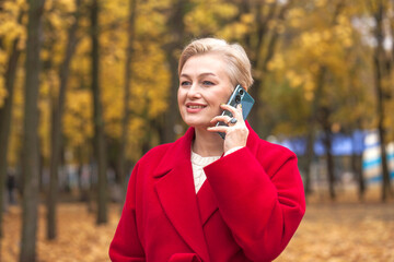 Portrait of a beautiful middle-aged woman in a red coat, autumn park