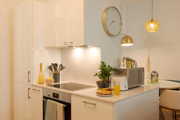 Detail of modern kitchen with induction plates and hood with lights on. There is breakfast ready to be served.