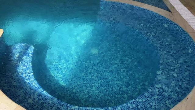 Empty Swimming pool with waterfall jet and jacuzzi in action