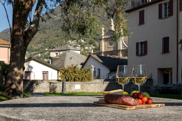 Outdoor patio with stone table with a chopping board with salami and cheese on top for an aperitif....