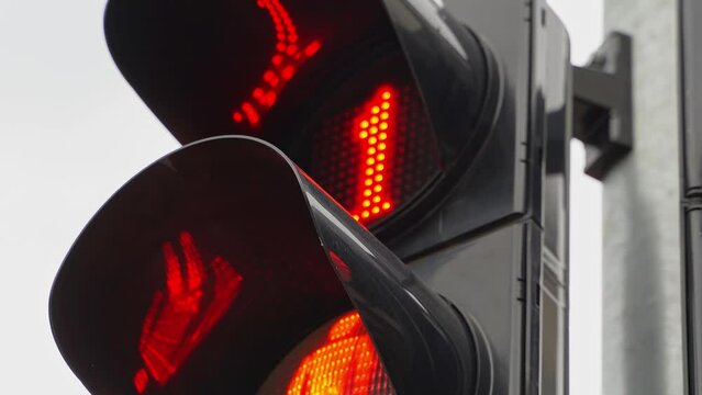 A close-up of a black traffic light counts down the time for pedestrians with a red forbidding signal. A red prohibiting signal prohibiting the movement of pedestrians or vehicles.
