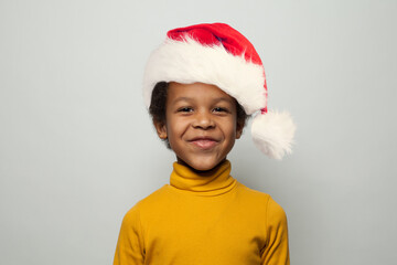 Portrait of happy little black kid boy in Santa hat smiling on white background