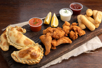 Picada board with nugget empanadas and tequeños with lemon slices and white and spicy sauces