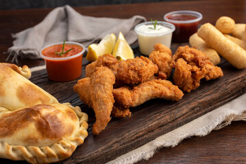 Picada board with nugget empanadas and tequeños with lemon slices and white and spicy sauces