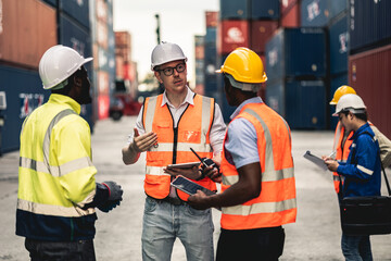 Container operator holding a walkie talkie to give instruction to other team member working in...