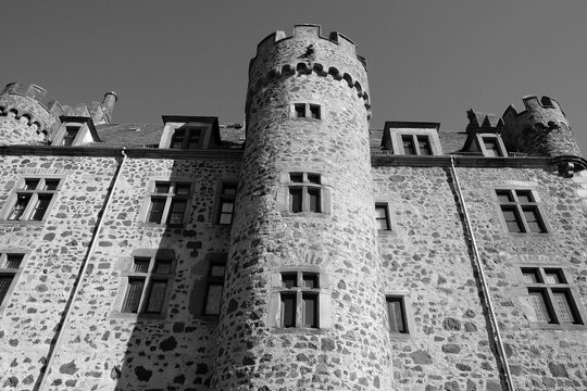 Alter Turm mit Zinnen und altes Mauerwerk aus Naturstein der Unterburg von Burg Staufenberg vor blauem Himmel im Sonnenschein in Staufenberg im Kreis Gie&szlig;en in Hessen in neorealistischem Schwarzwei&szlig;