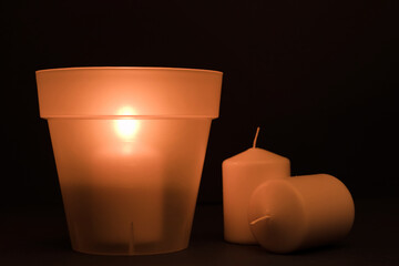concept energy cuts, DIY lamp, pot and candle indoors, on the desk, dark blue background